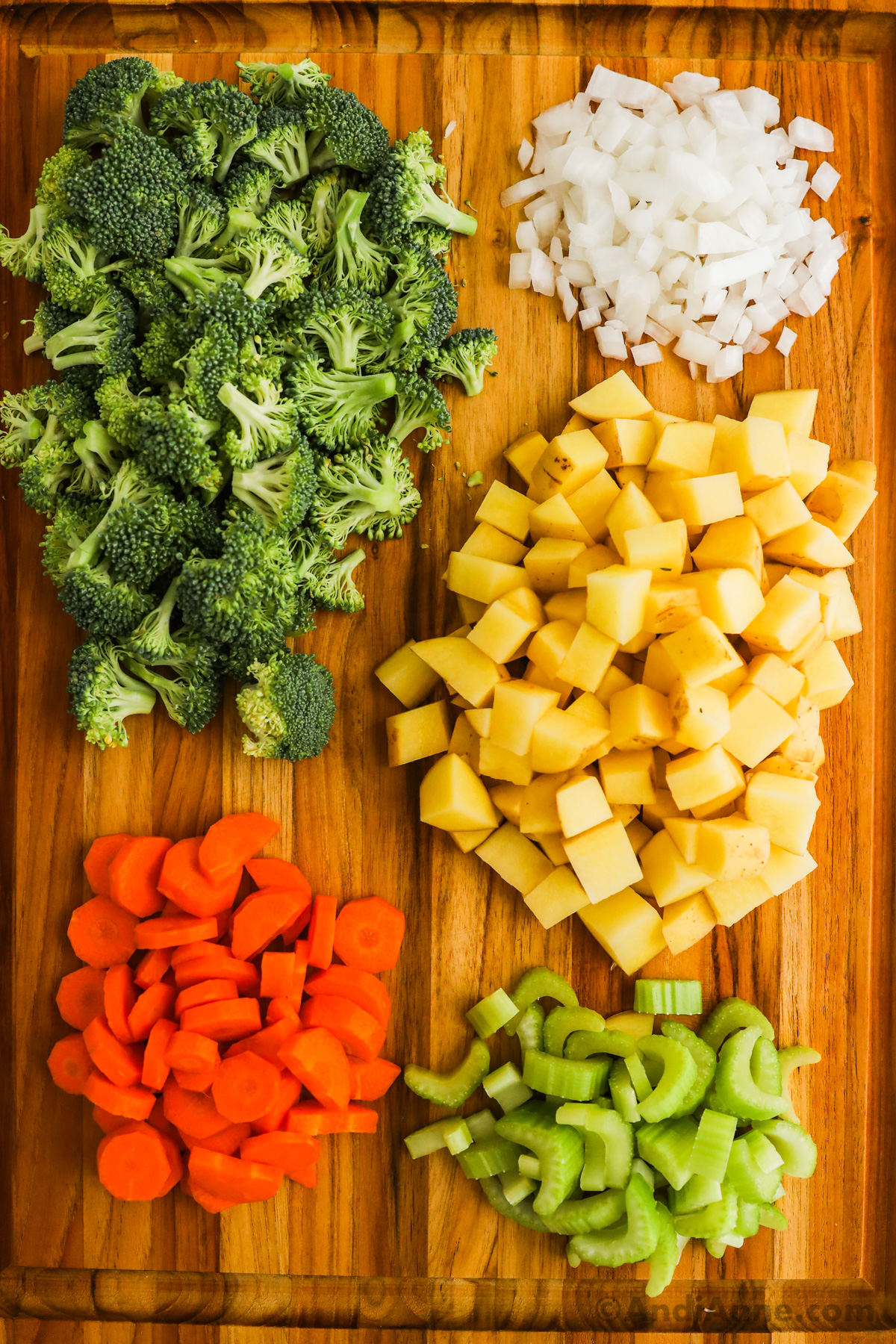 Chopped broccoli, onion, potatoes, carrots and celery on a cutting board