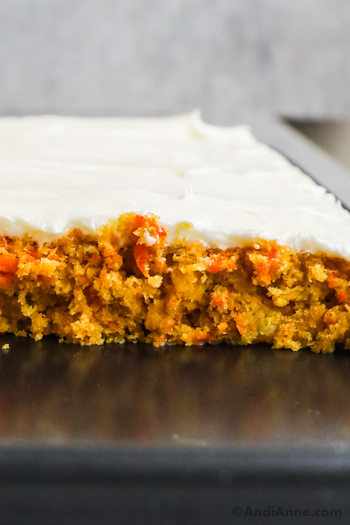 Close up of a slice of carrot cake with cream cheese frosting on top