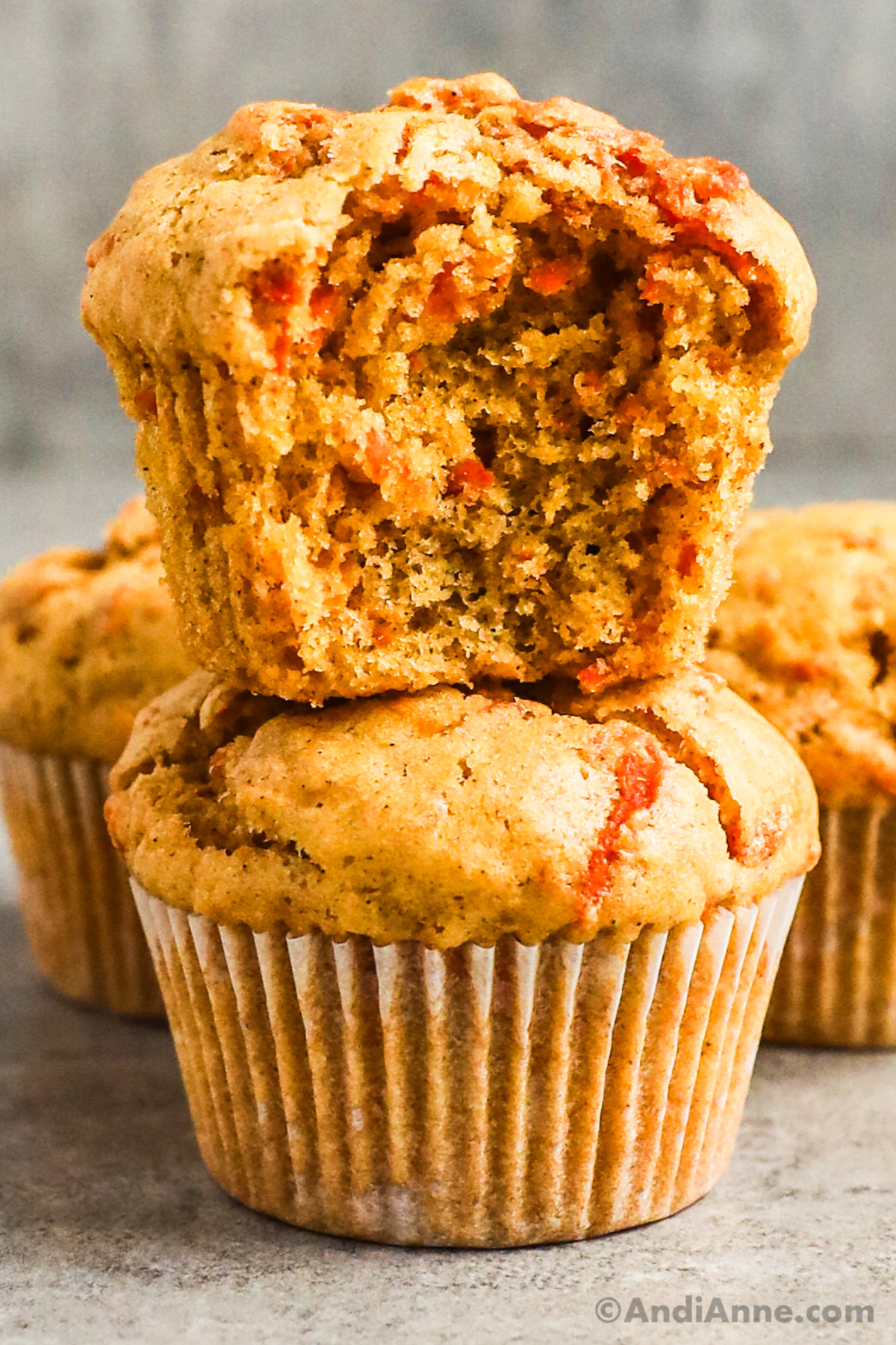 One muffin cut in half stacked on top of another carrot muffin