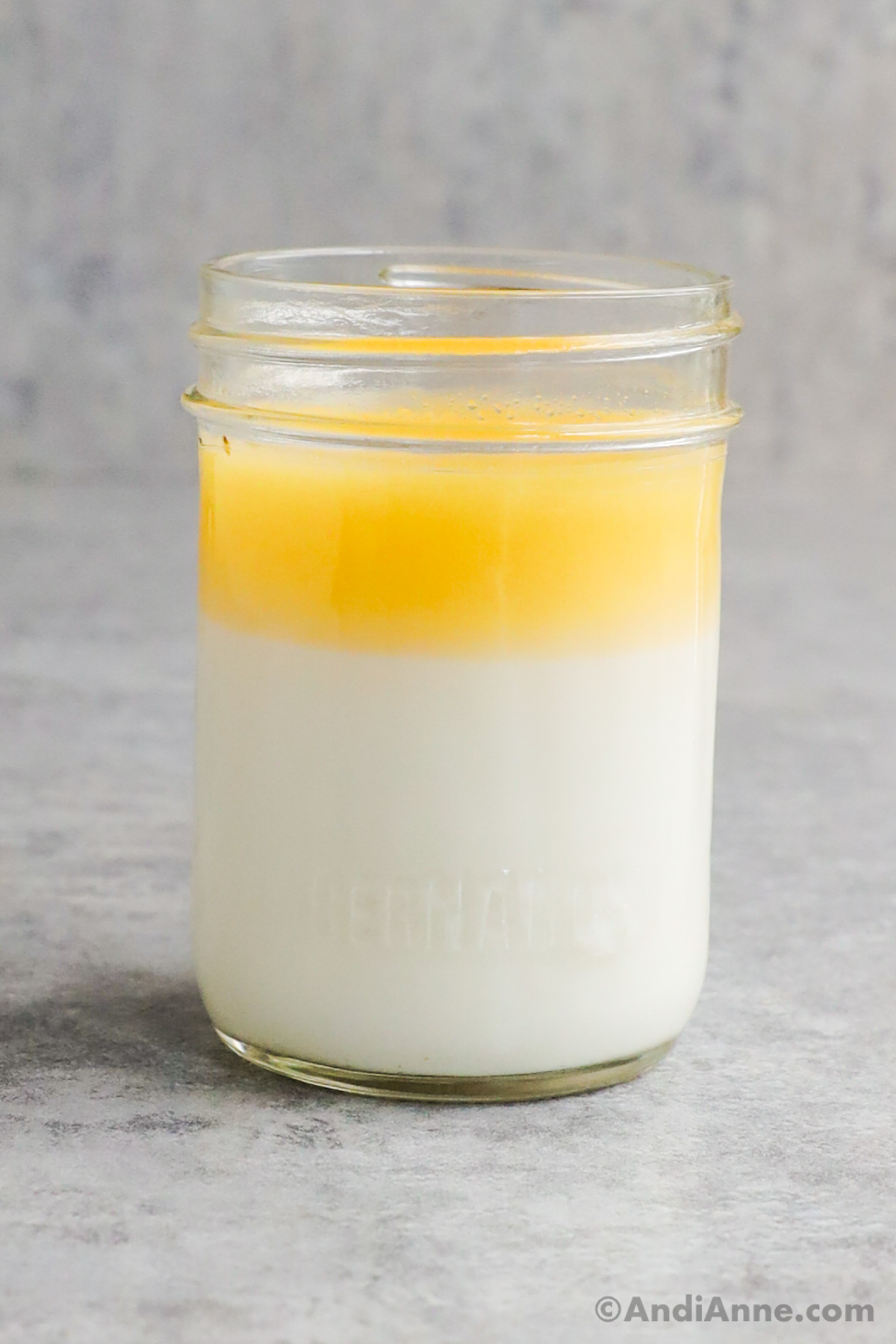 A mason jar with a white layer and yellow layer of heavy cream that's separated.