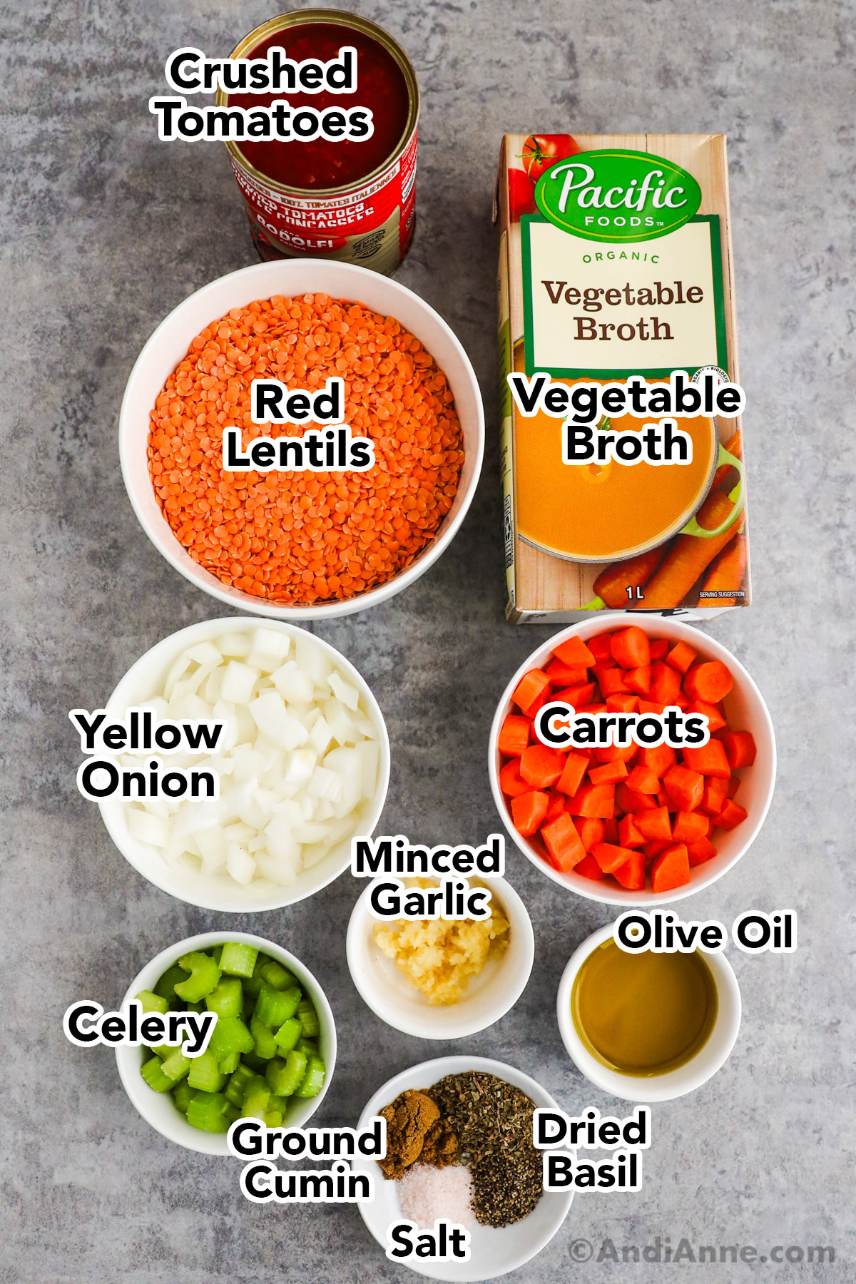 Recipe ingredients in bowls including red lentils, vegetable broth, canned crushed tomatoes, yellow onion, carrots, celery, minced garlic, olive oil, and spices