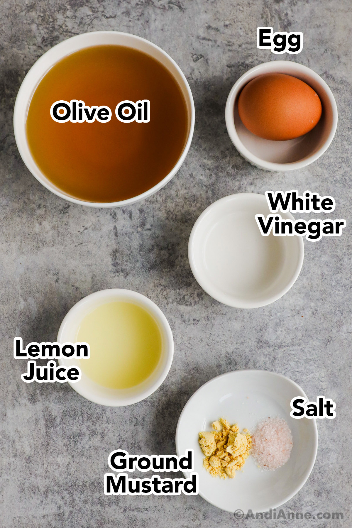 Ingredients in bowls including olive oil, an egg, white vinegar, lemon juice, ground mustard and salt.