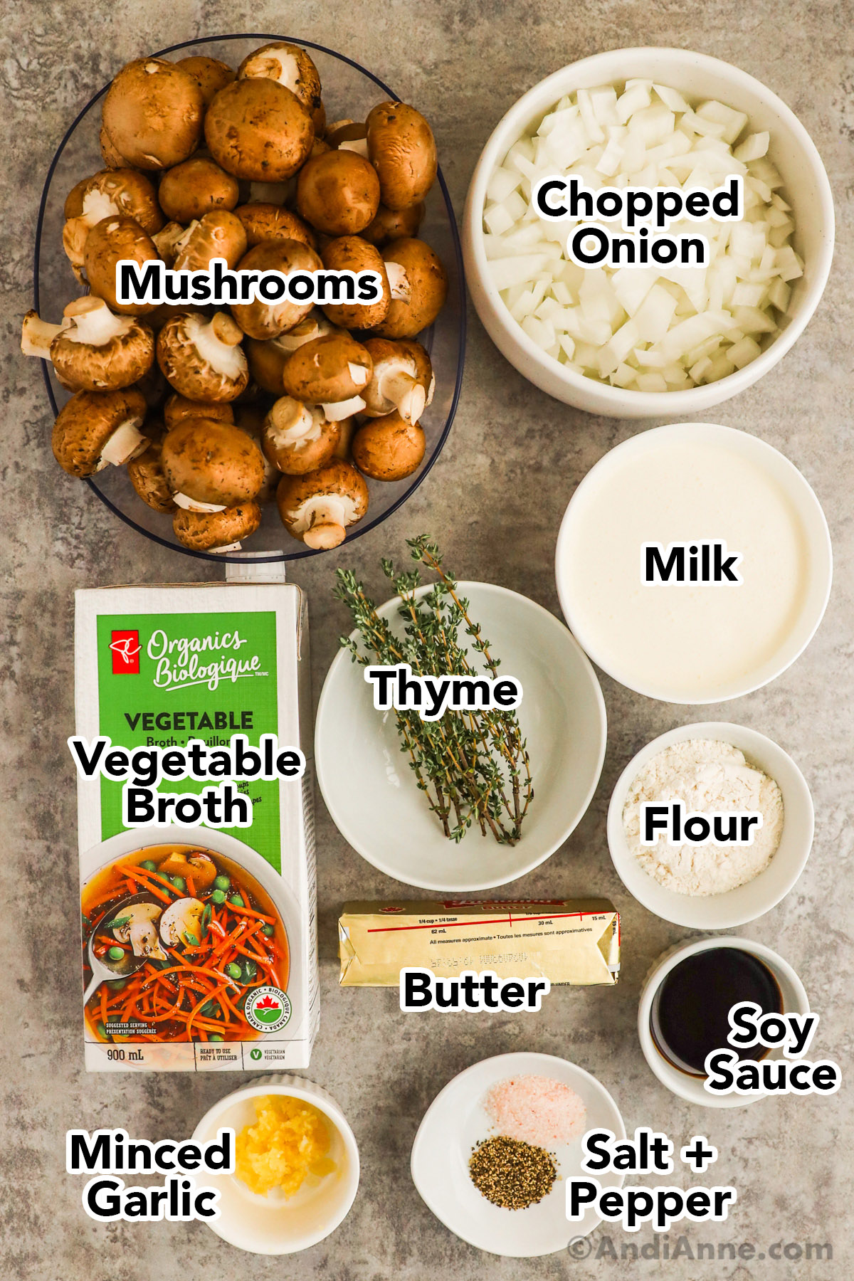 Recipe ingredients in containers including bowl of mushrooms, chopped onion, milk, thyme, flour, soy sauce, minced garlic, carton of vegetable broth and stick of butter