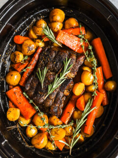 Looking down into a slow cooker with pot roast, potatoes, and carrots.