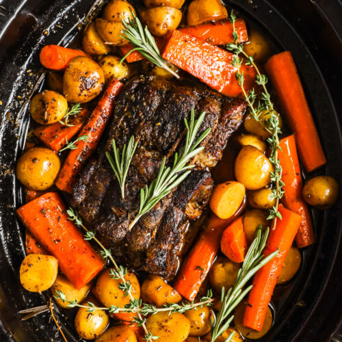 Looking down into a slow cooker with pot roast, potatoes, and carrots.