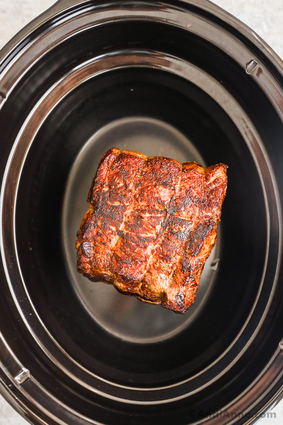 A slow cooker with a seared beef roast inside