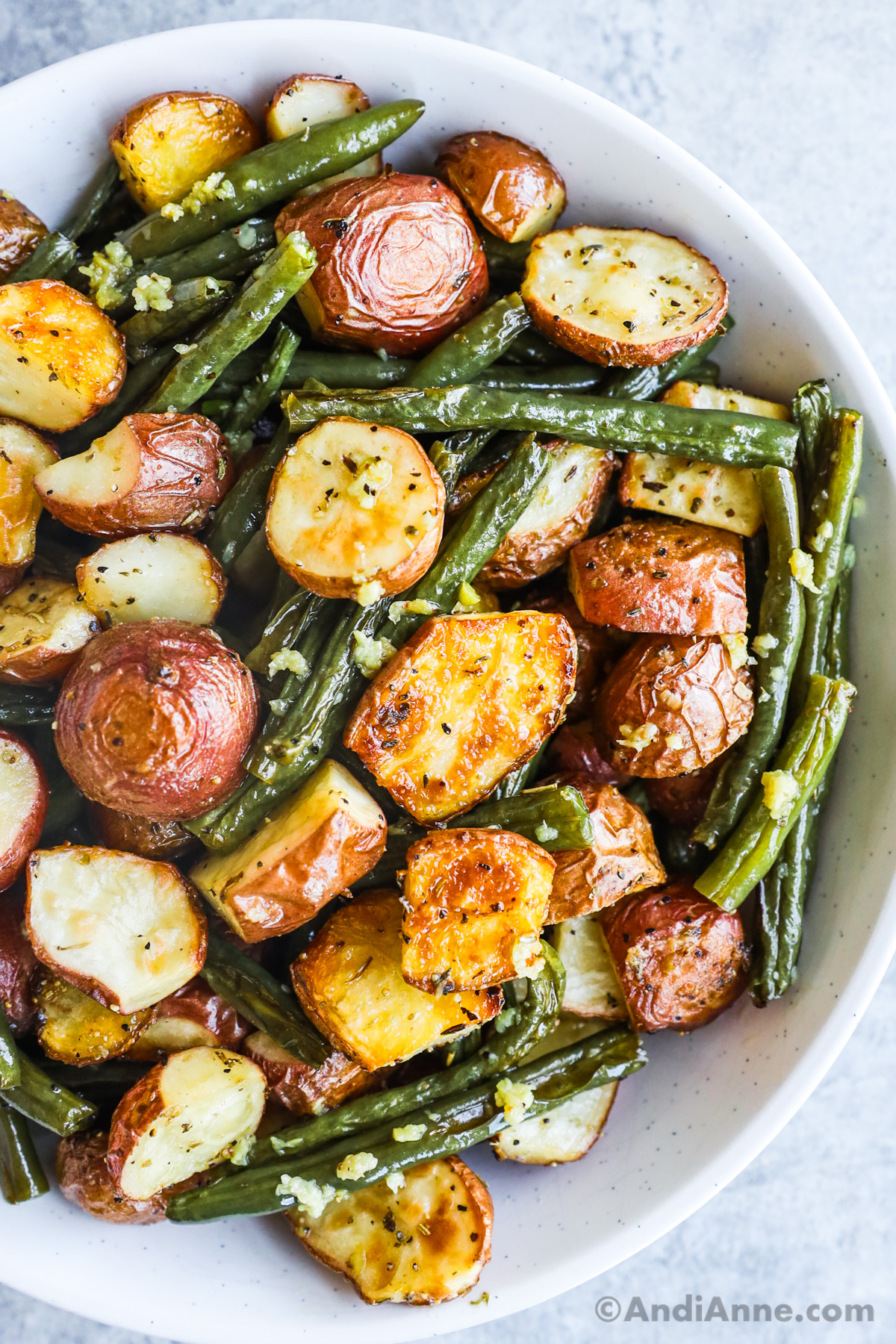 Close up of a bowl of baked baby potatoes and green beans.