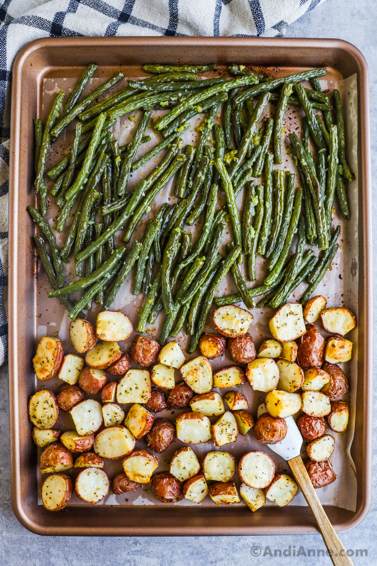 A sheet pan with crispy potatoes on one side and cooked green beans on the other