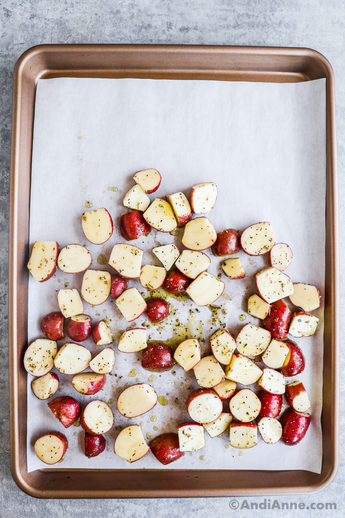 A sheet pan with seasoned sliced potatoes uncooked.