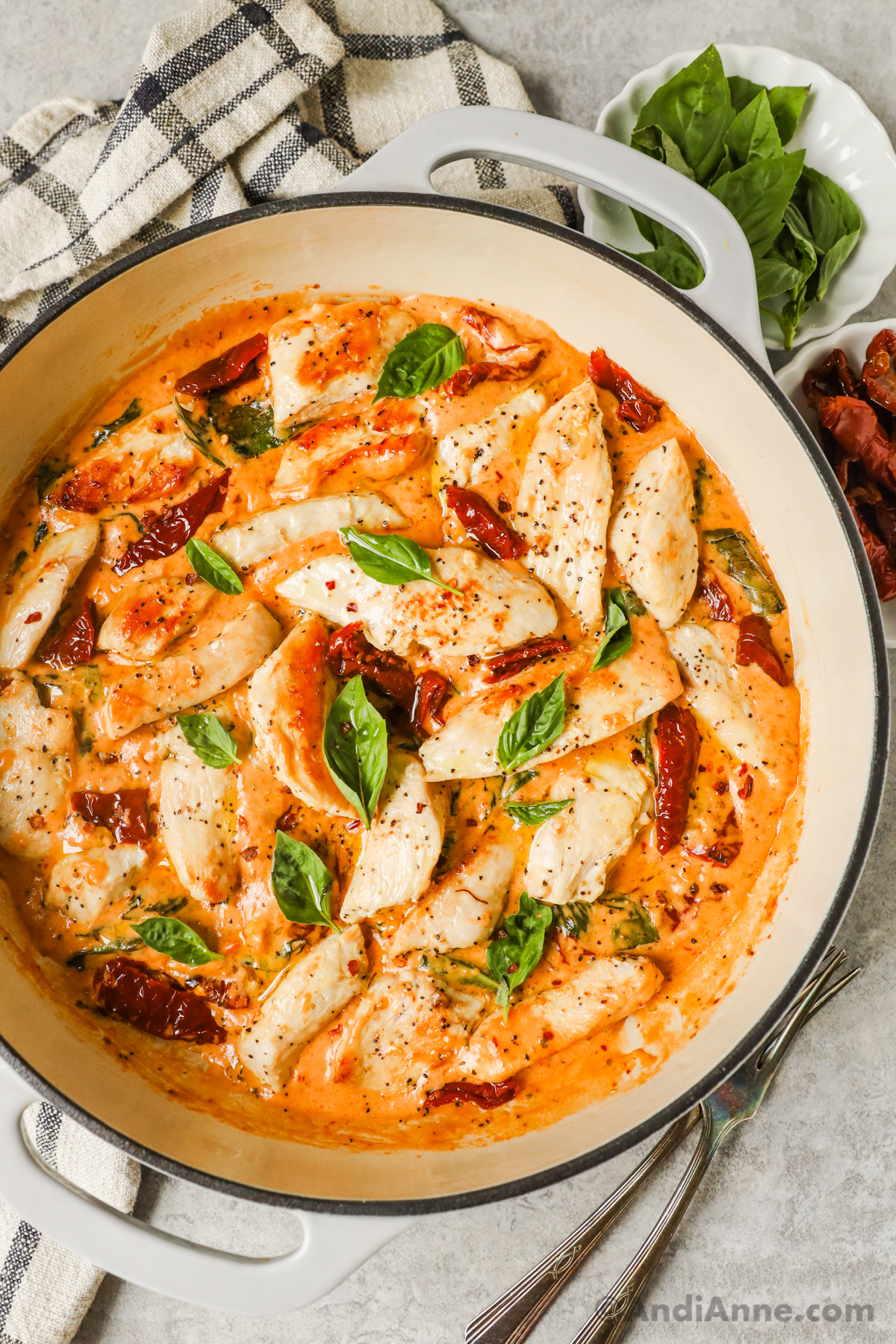 A skillet with marry me chicken recipe with sun dried tomatoes and basil.