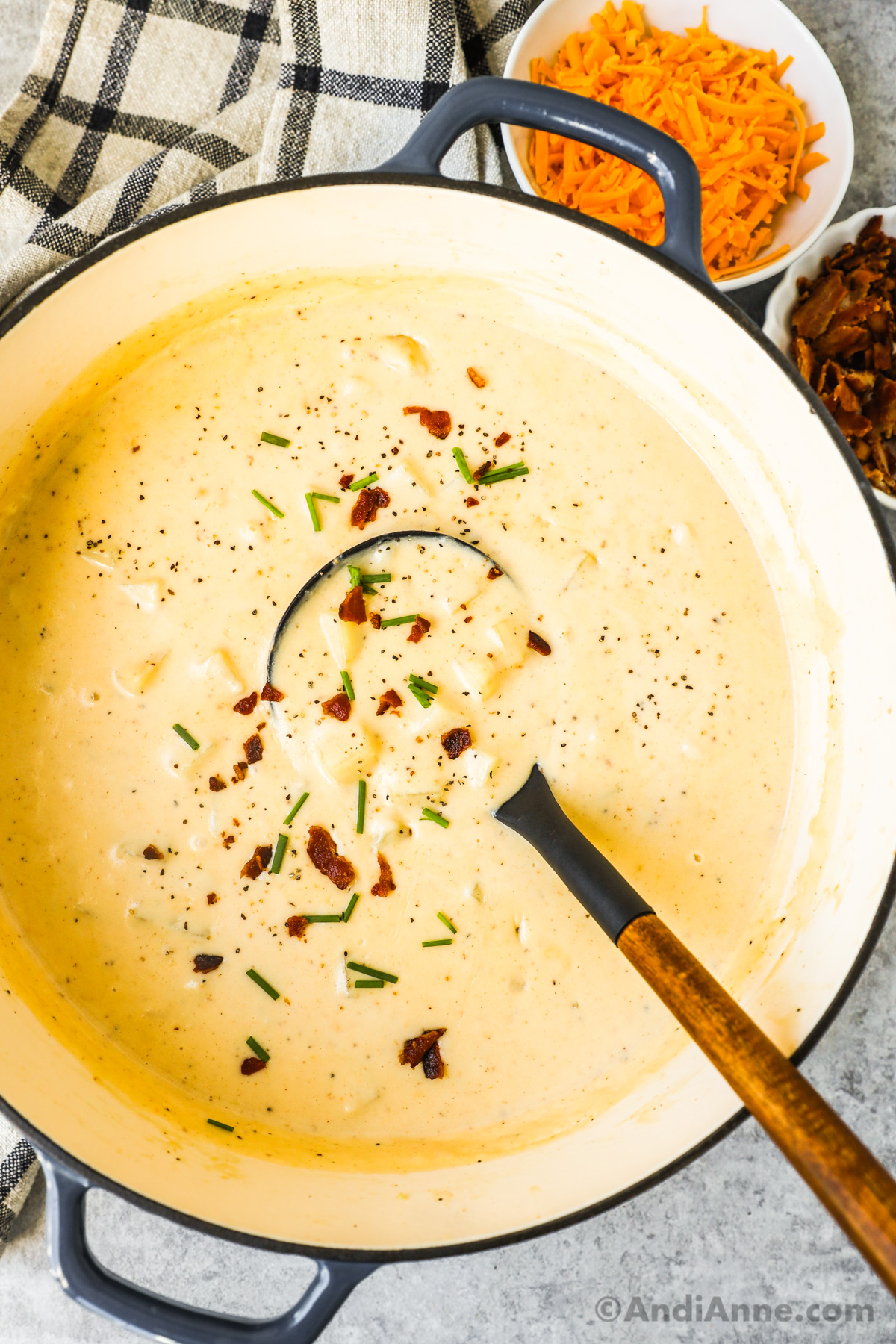 Looking down into a bowl of creamy potato soup with a sprinkle of chives and crumbled bacon.