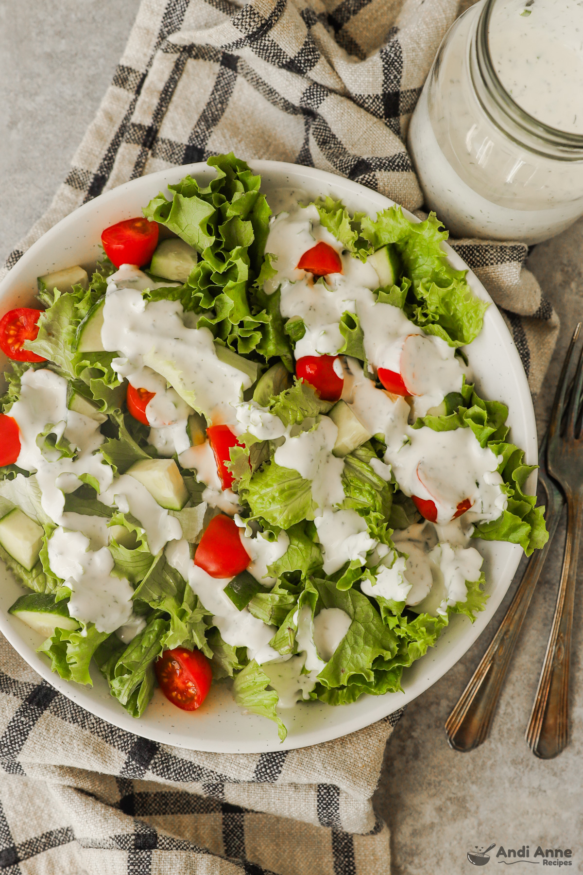 A plate with a salad and ranch dressing drizzled on top. 