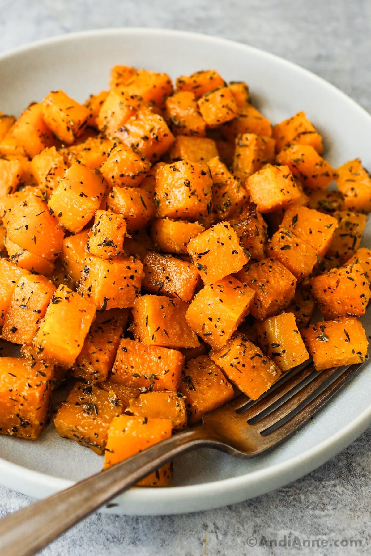 Close up of butternut squash cubes seasoned with spices.