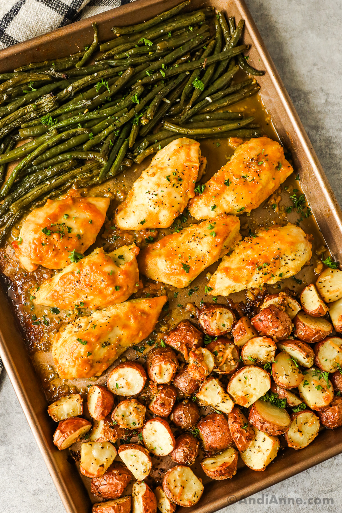 A baking sheet with chicken breasts, potatoes and green beans