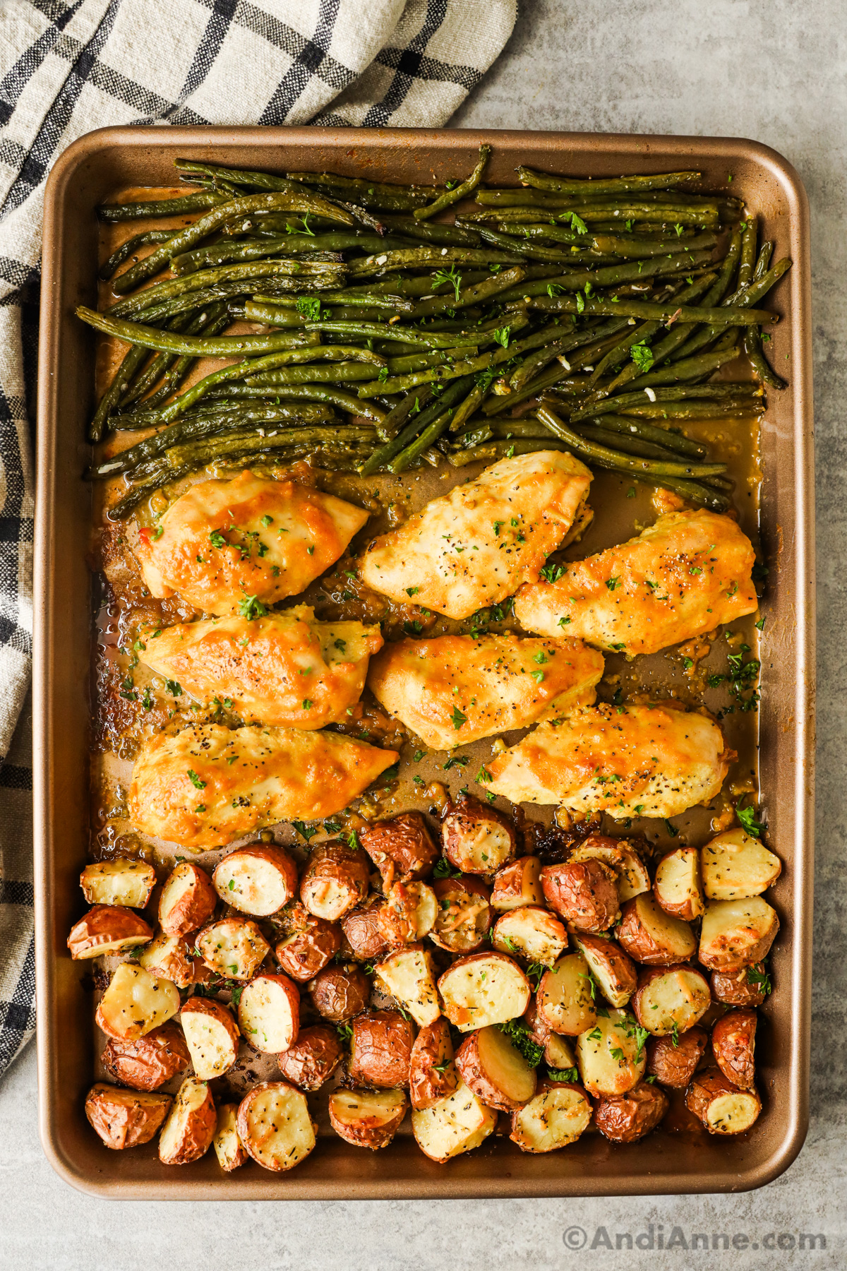 Fully cooked chicken breast, green beans and potatoes on a baking sheet.