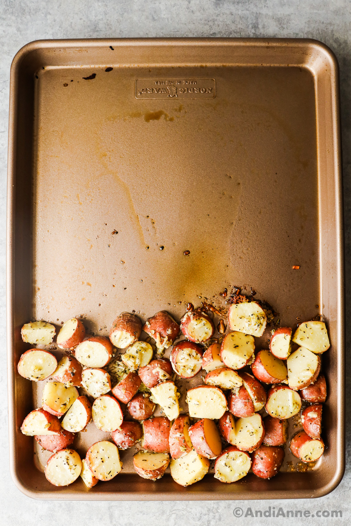 Sheet pan with sliced baby red potatoes on one side.