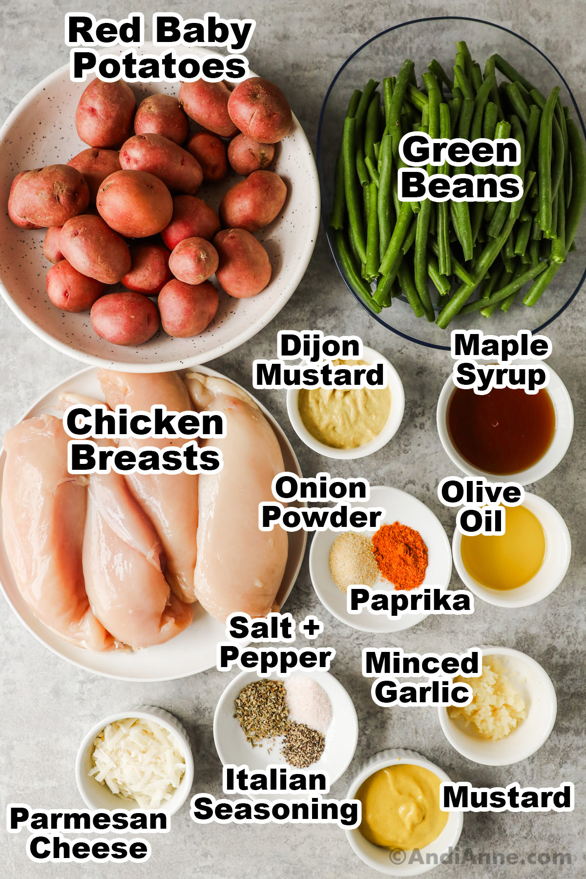 Bowls with baby potatoes, green beans, raw chicken breasts, bowls of mustard, maple syrup, spices and oil.