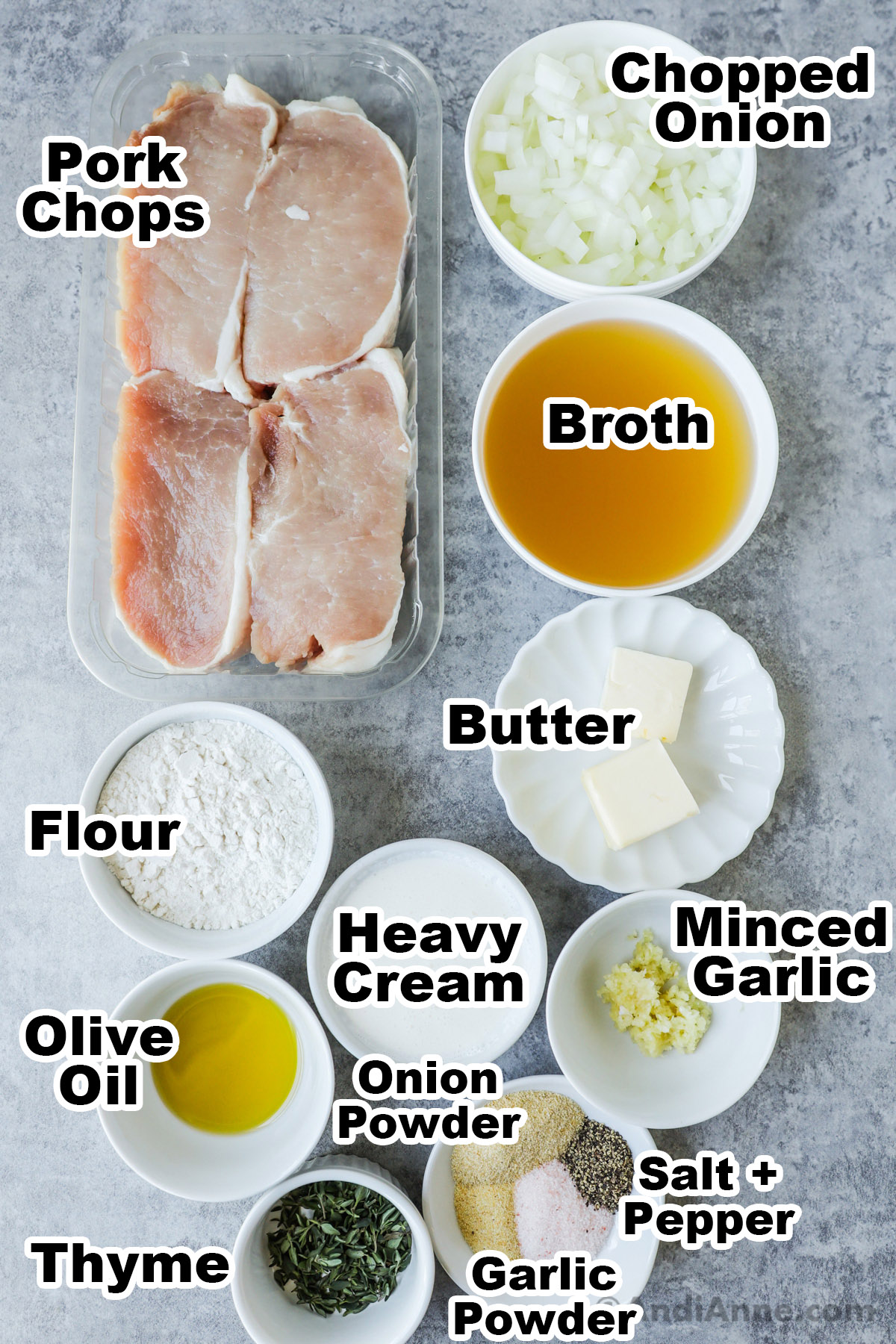 A tray of raw pork chops, bowls of chopped onion, broth, flour, butter, heavy cream, olive oil, spices and minced garlic.