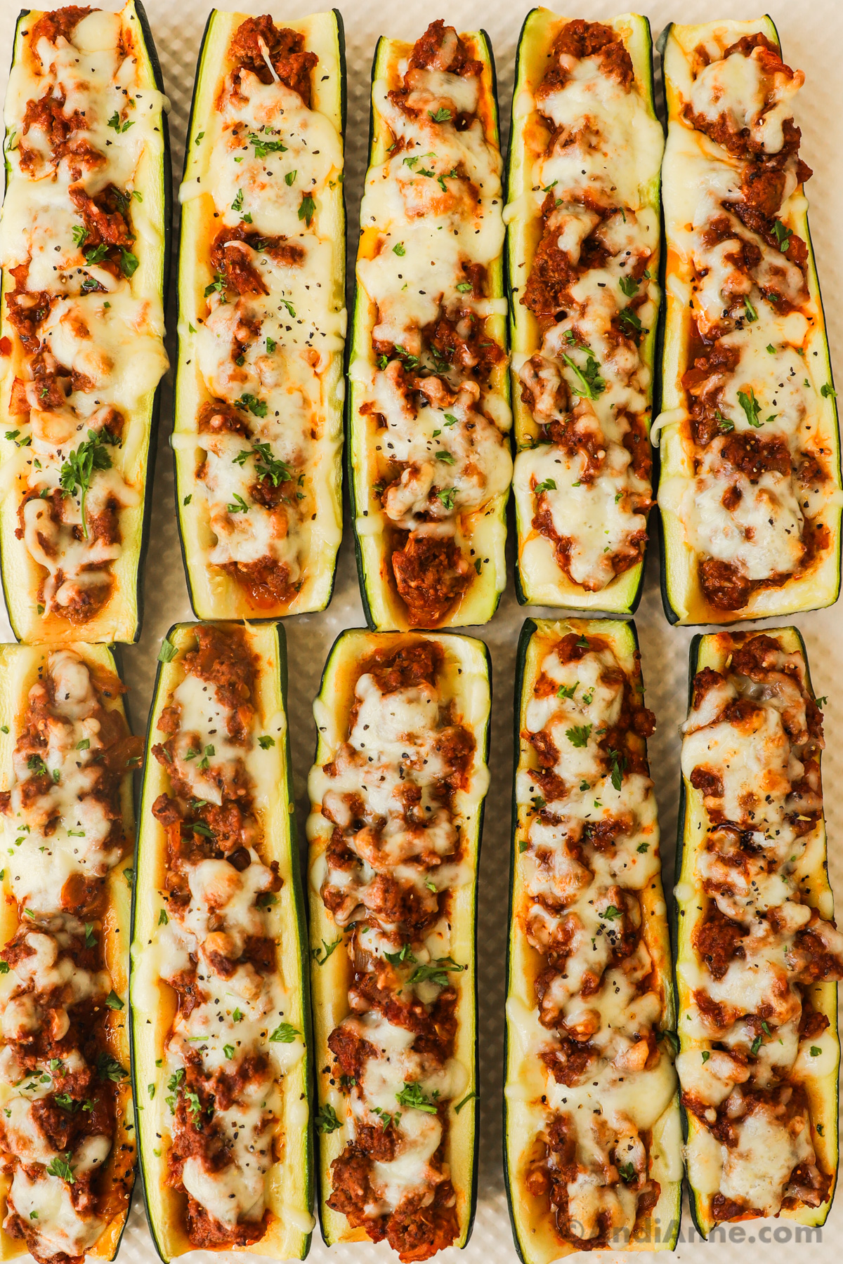 close up of zucchini boats stuffed with ground beef mixture and topped with mozzarella cheese.