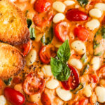 A bowl of tomato basil butter beans recipe with two bread slices on the side