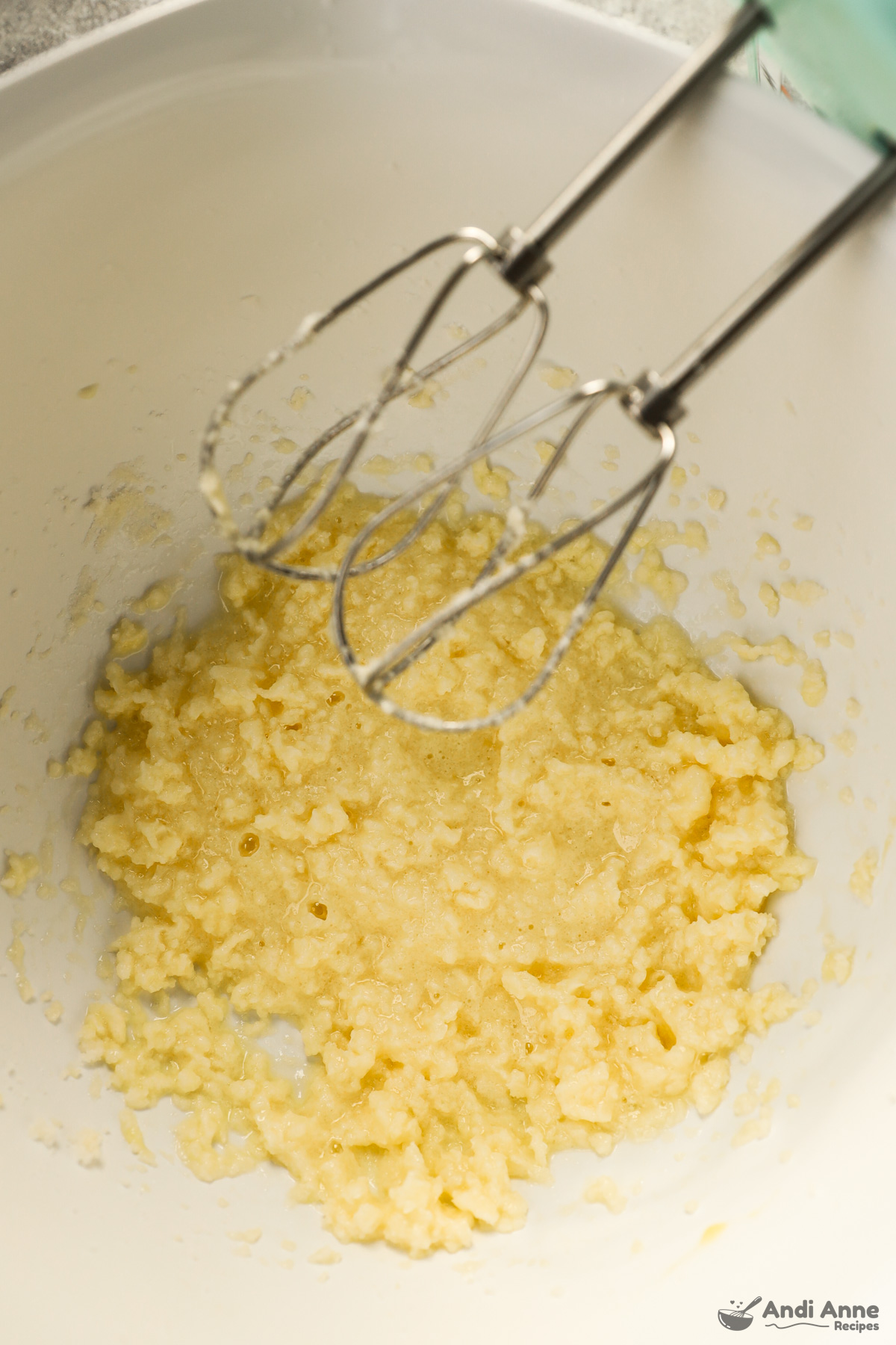 Mixture of egg, butter and sugar in bowl with hand mixer