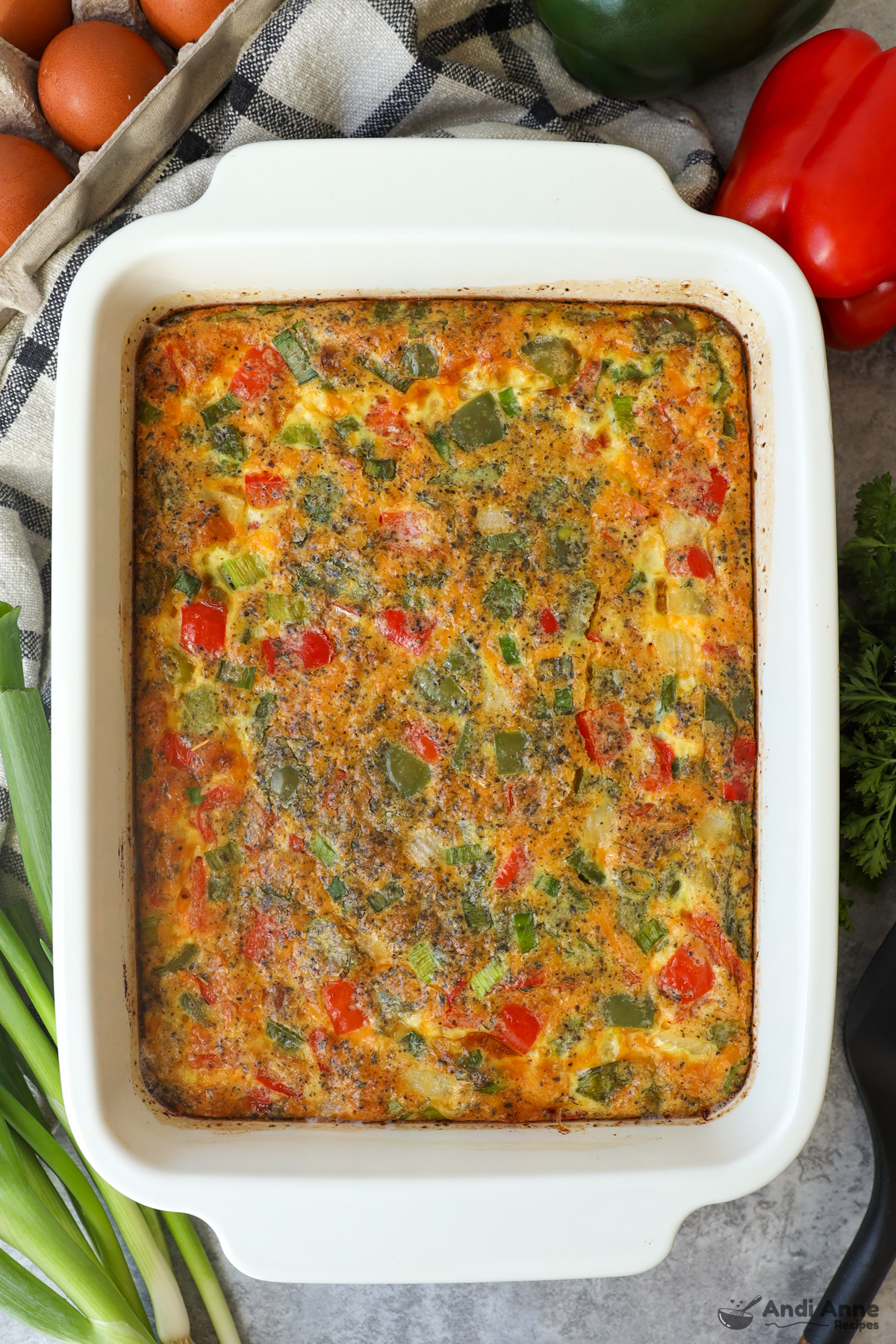 White casserole dish with egg breakfast casserole with bell peppers and spices.