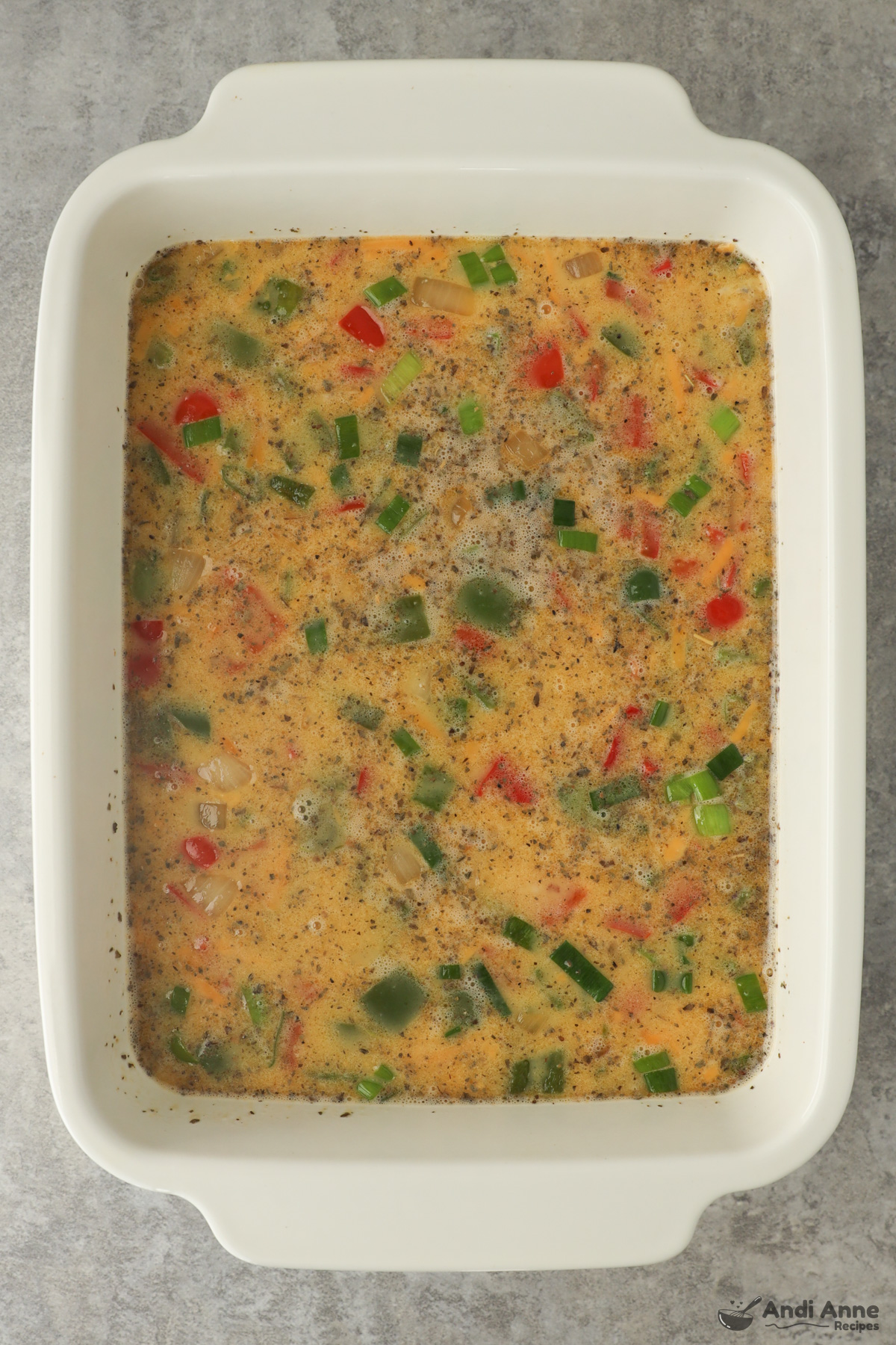 A casserole dish with uncooked egg casserole ingredients dumped in.