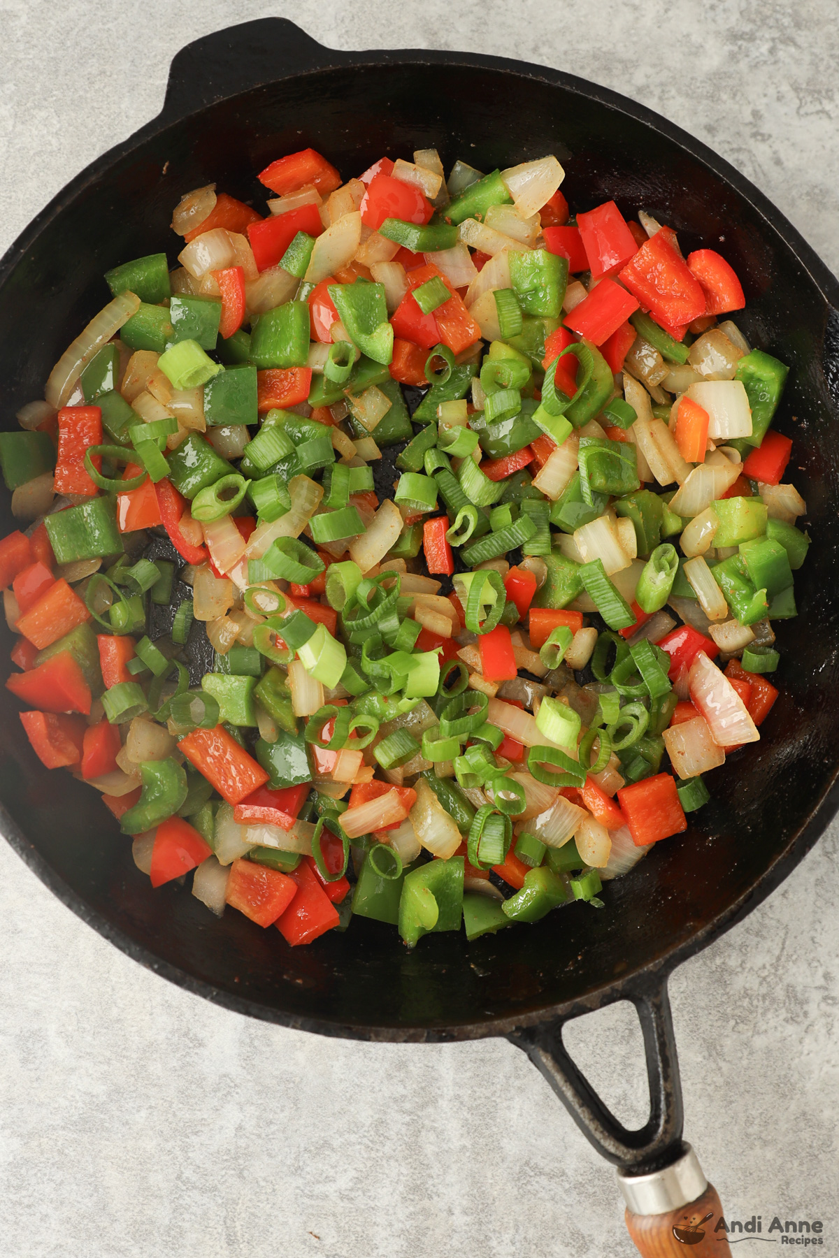 Frying pan with chopped bell pepper, onion and green onion.