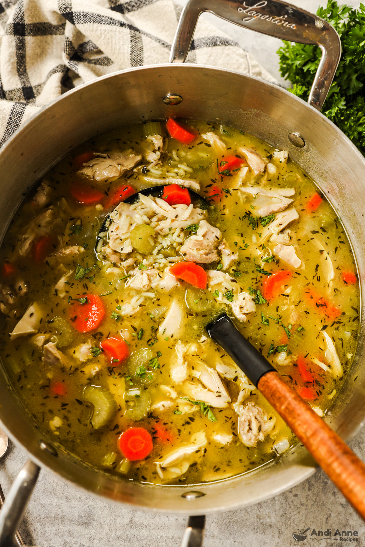 A pot of chicken and rice soup with a soup ladle