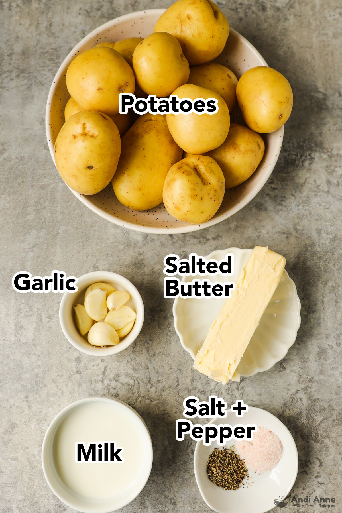 Bowl of yellow potatoes, bowls of garlic cloves, stick of butter, milk, salt and pepper.