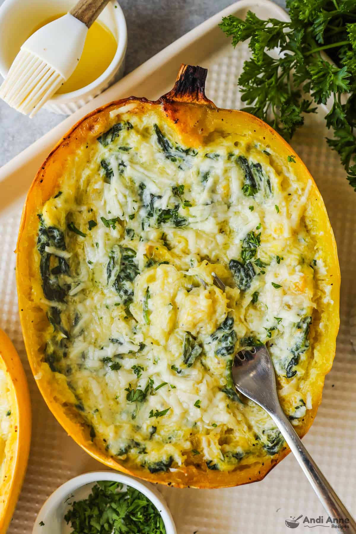 Half of a cooked spaghetti squash with creamy spinach parmesan sauce inside.