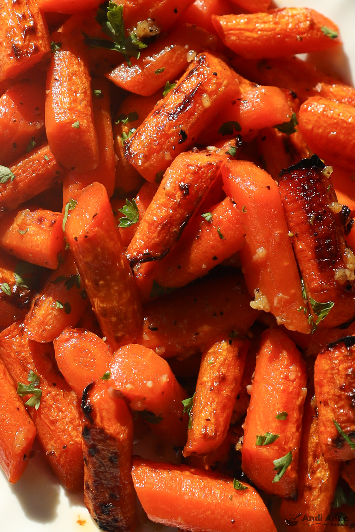 Close up of honey garlic butter carrots, some of them a little charred, with bits of parsley for garnish