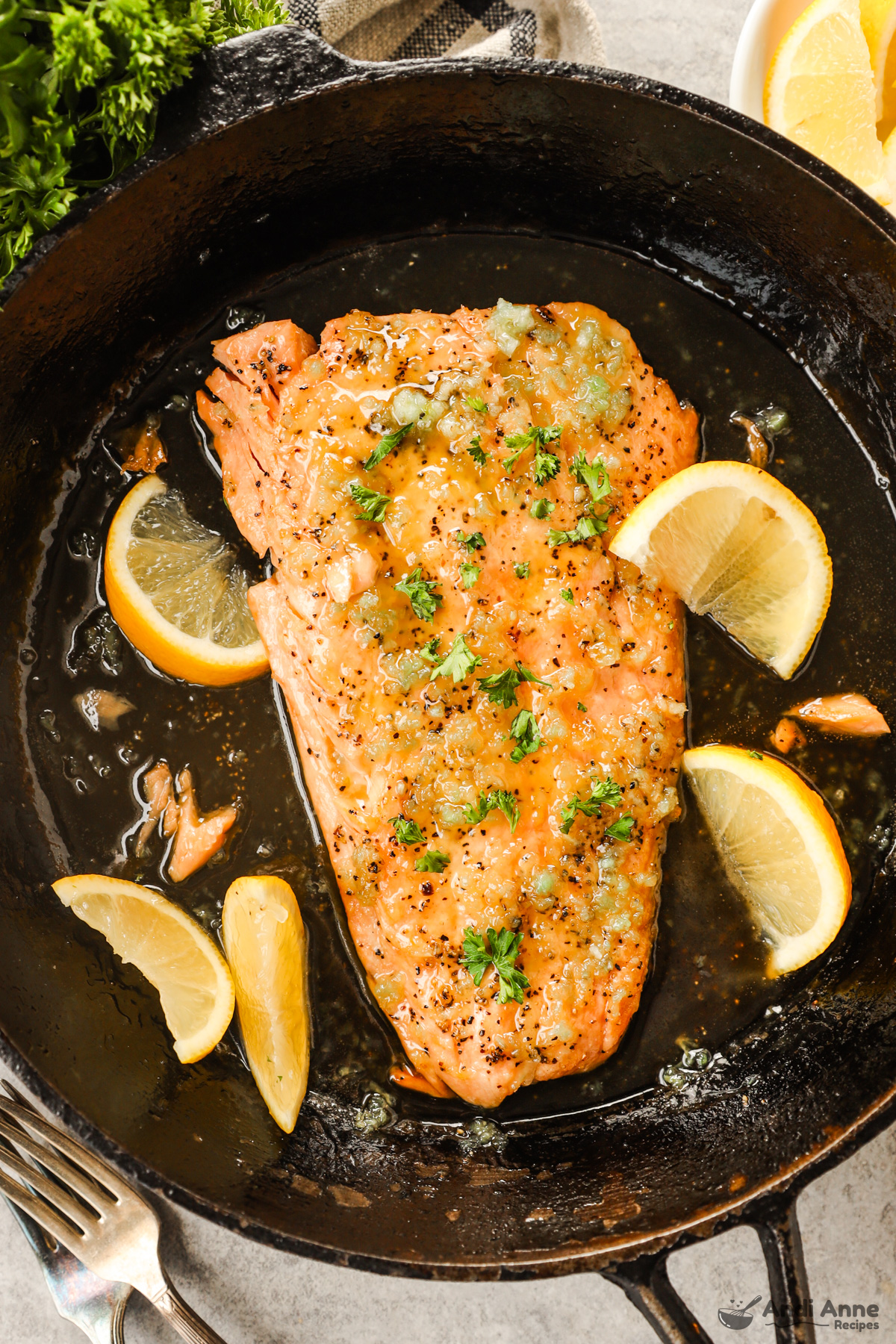 Salmon fillet in a skillet with sliced lemons in a honey garlic sauce