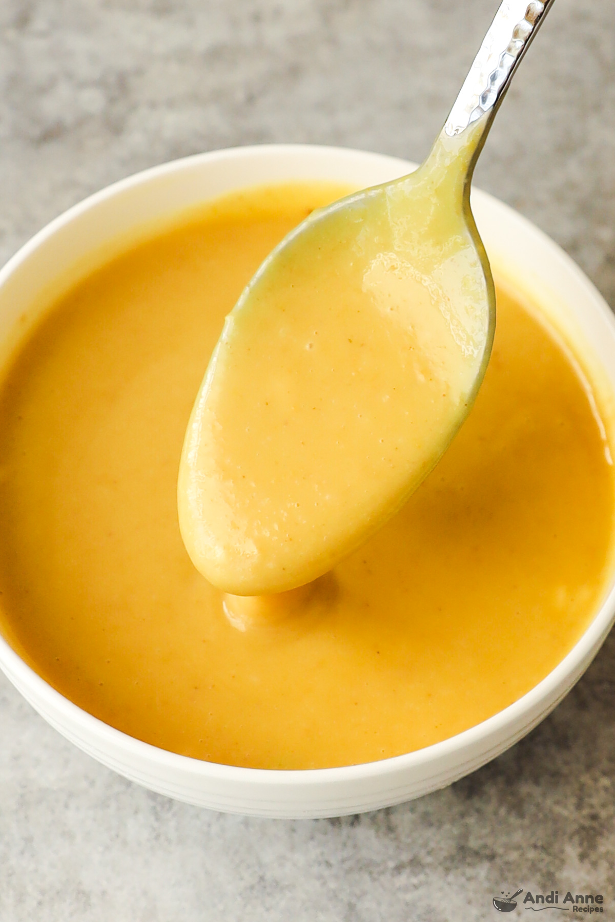 Bowl of honey mustard sauce with a spoon