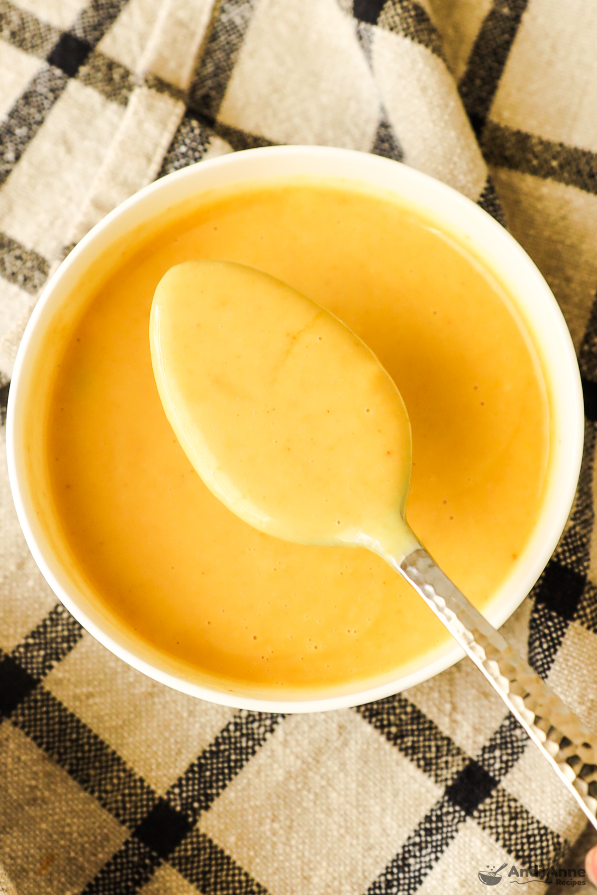 A bowl of honey mustard sauce with a spoon