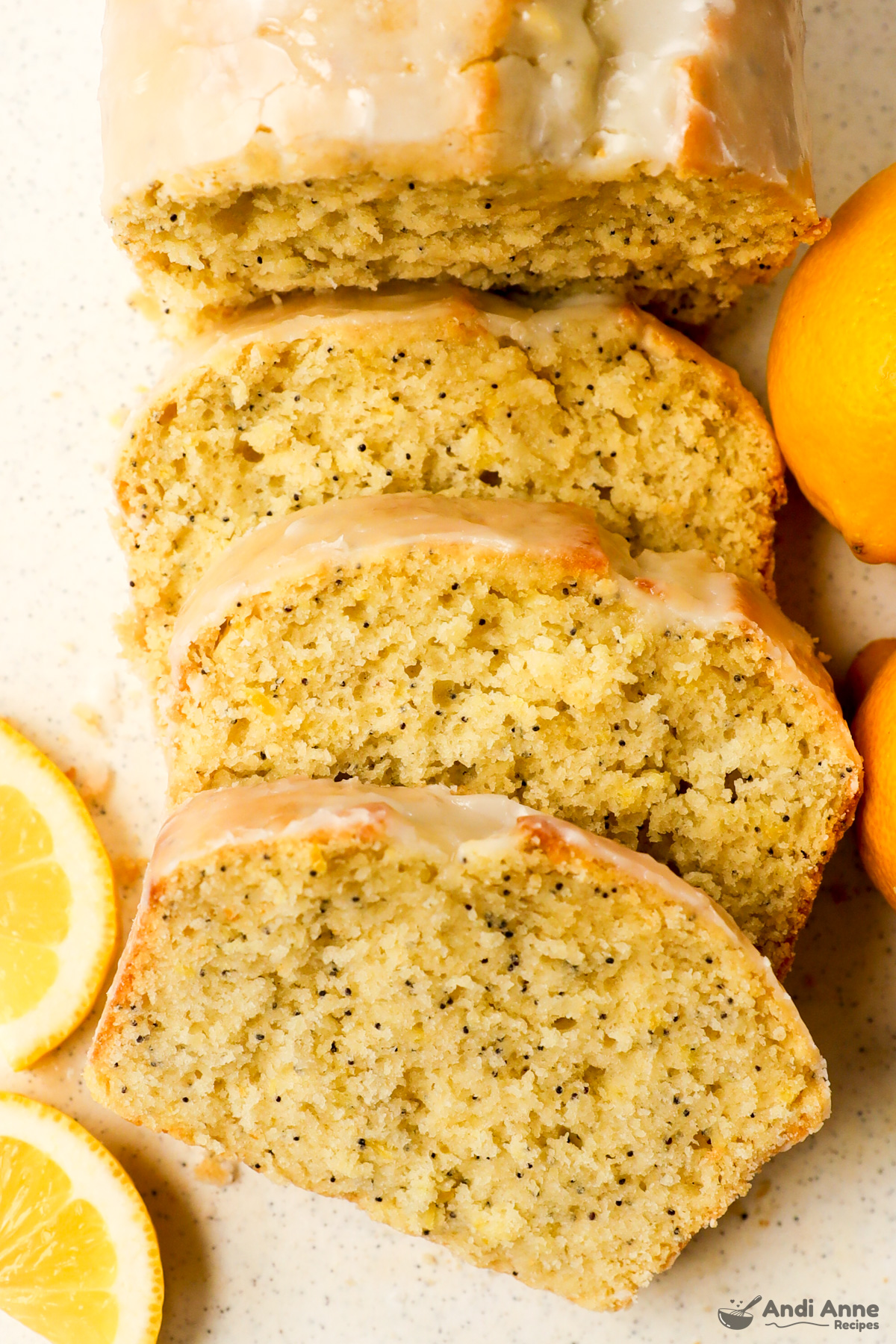 Sliced lemon poppyseed loaf with a few fresh lemons surrounding it. 