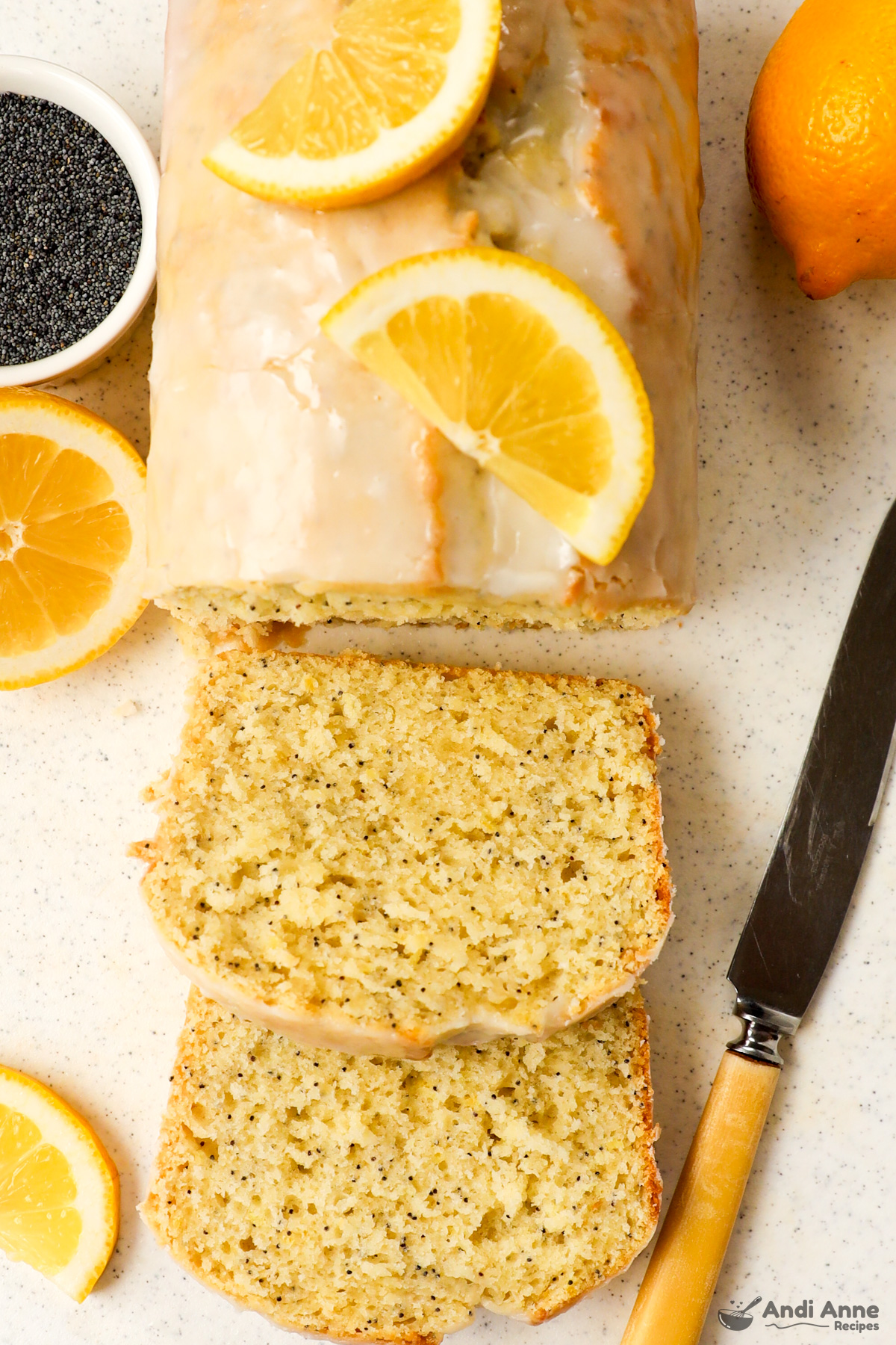 Lemon poppyseed loaf with a few slices cut off and sliced fresh lemon on top. 