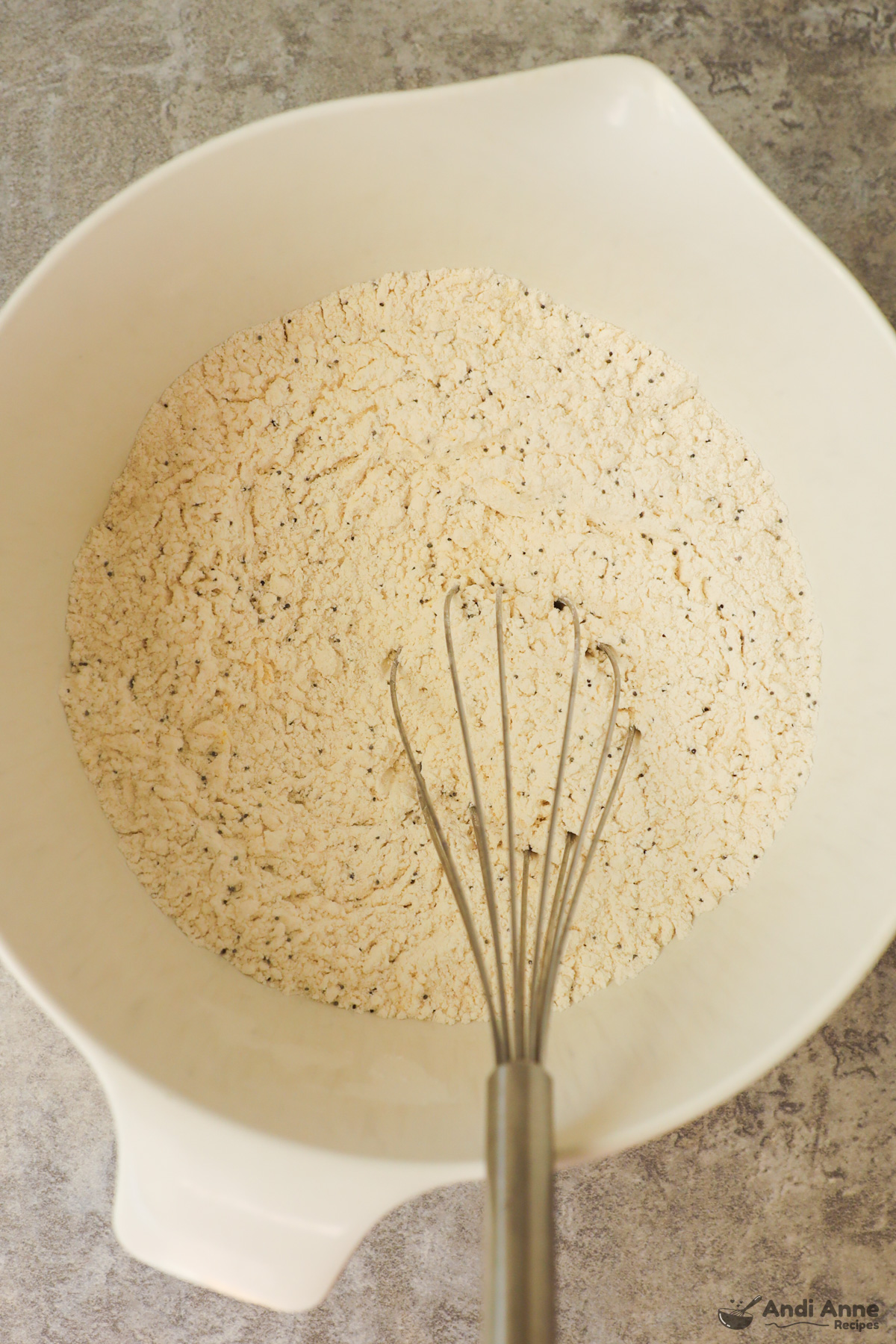 White bowl with dry ingredients and whisk.