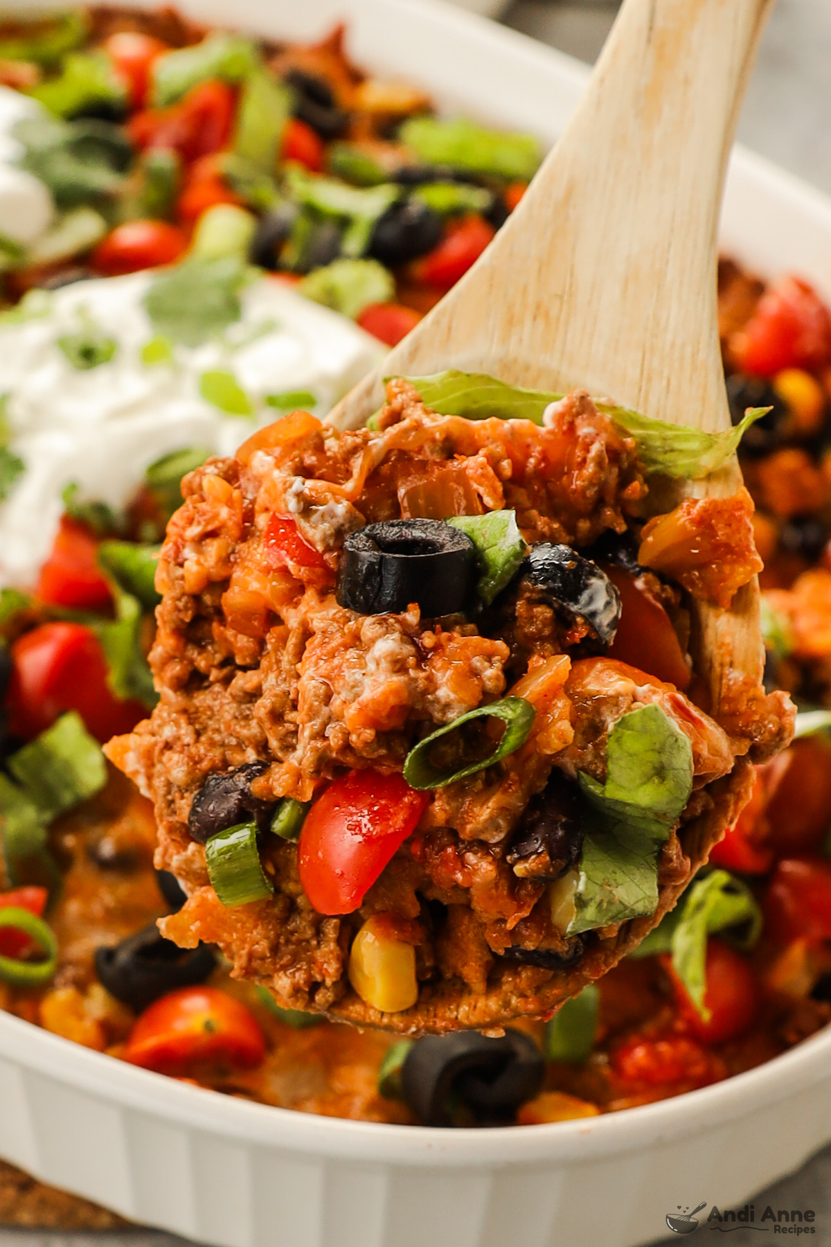 Close up of a wood spoon with taco casserole ingredients on it