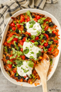 Taco casserole with sour ceam, shredded lettuce, olives and chopped tomato toppings