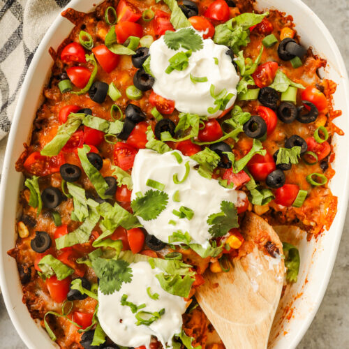 Taco casserole with sour ceam, shredded lettuce, olives and chopped tomato toppings