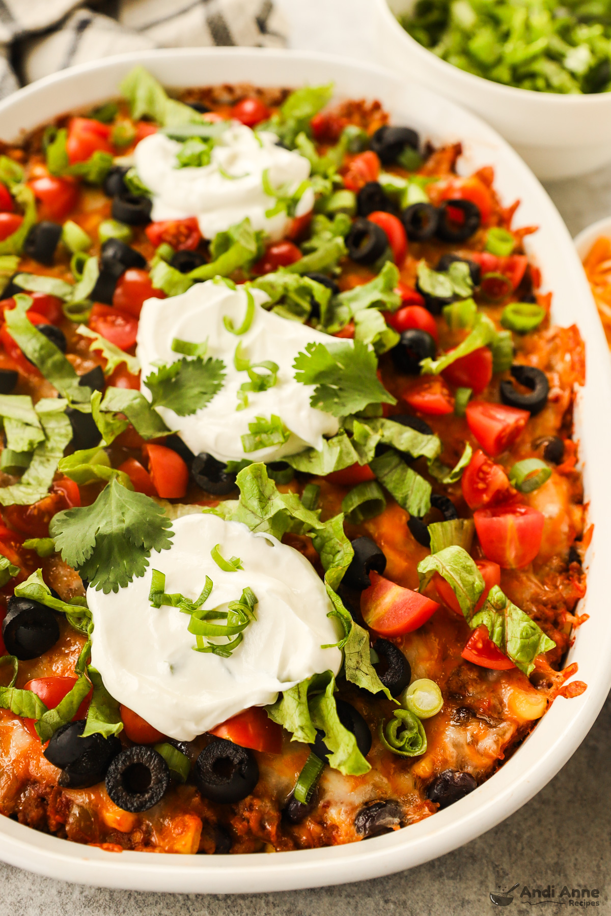 Close up of dollops of sour cream, shredded lettuce, tomatoes, cilantro and olives