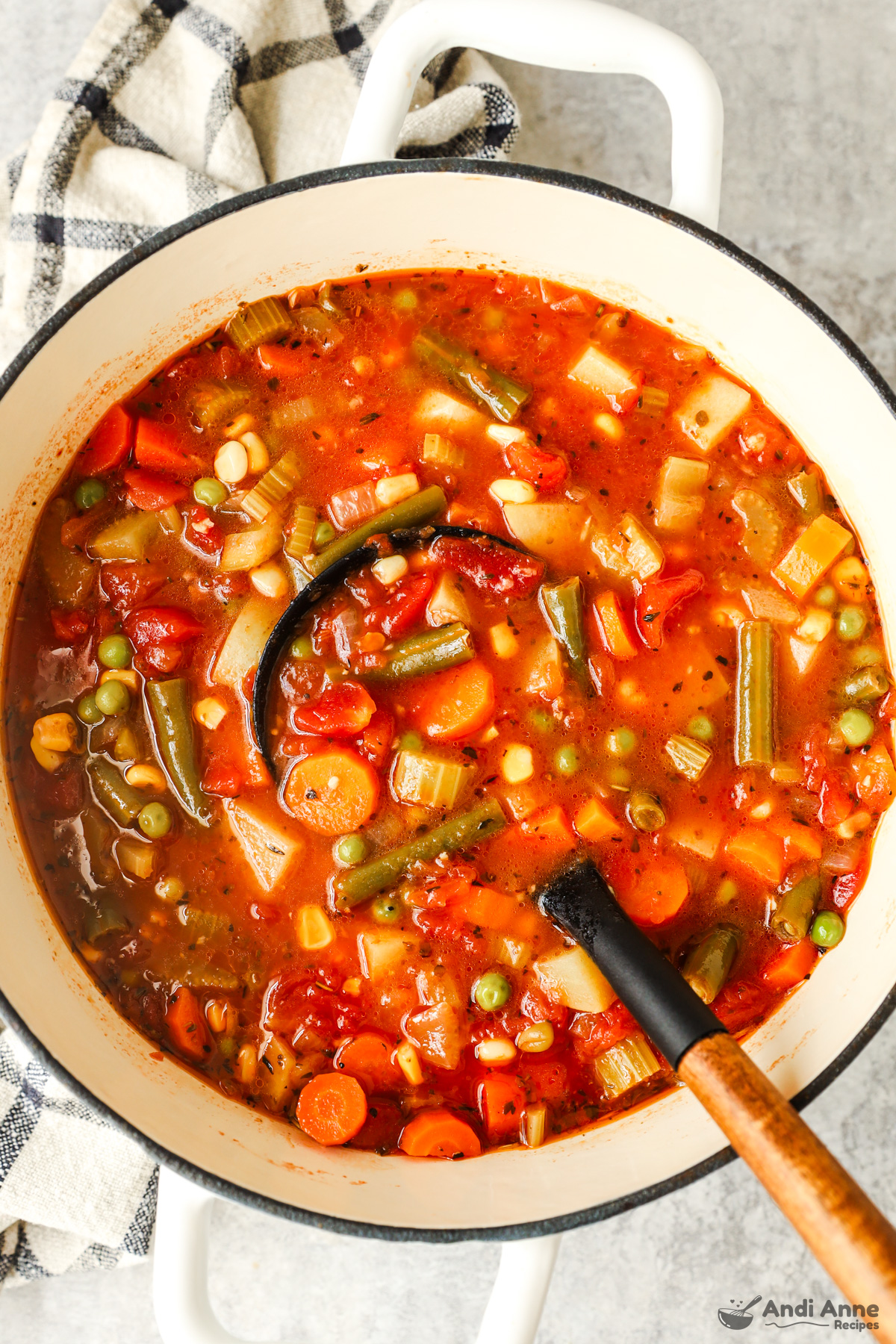 A pot of vegetable soup with a soup ladle.