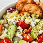 avocado tomato dip with feta and some crackers on the side