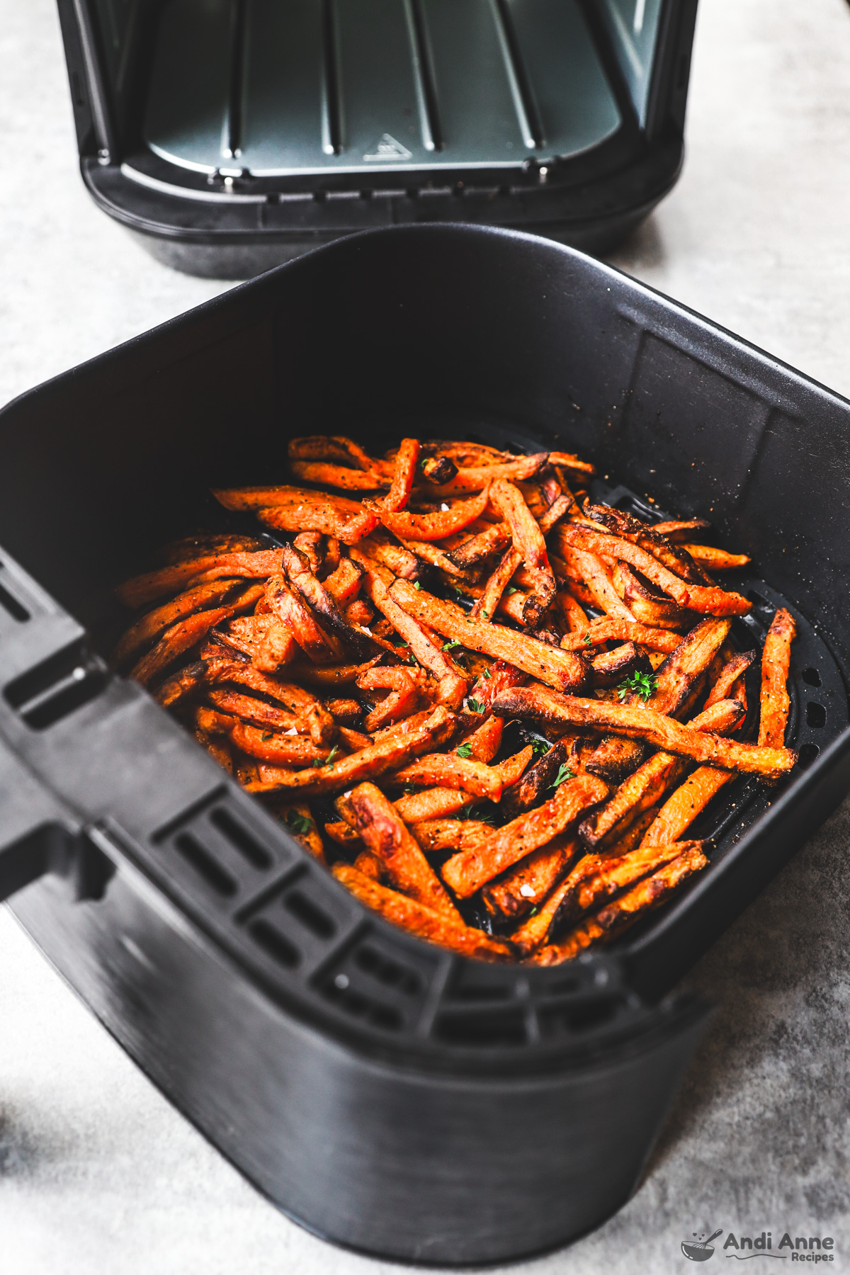 An air fryer basket with cooked sweet potato fries inside