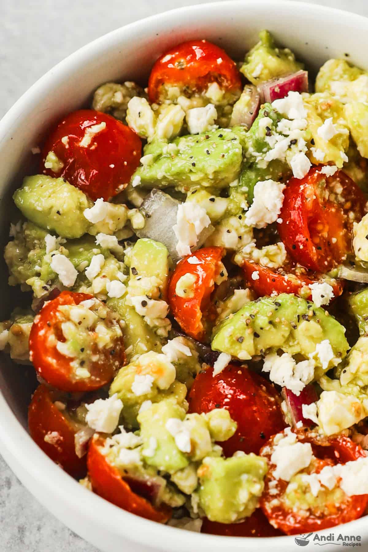 close up of avocado, tomato, onion and feta in a dip