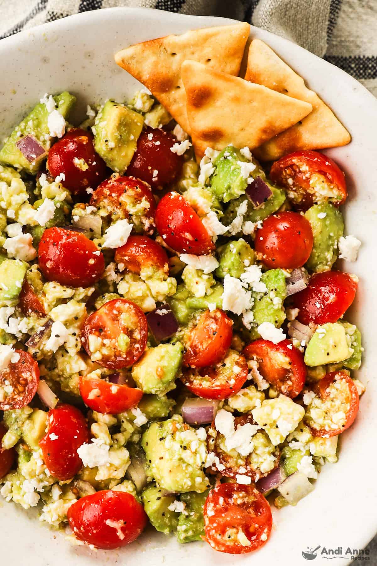 avocado, tomato, onion, feta dip in a bowl with a few crackers on the side