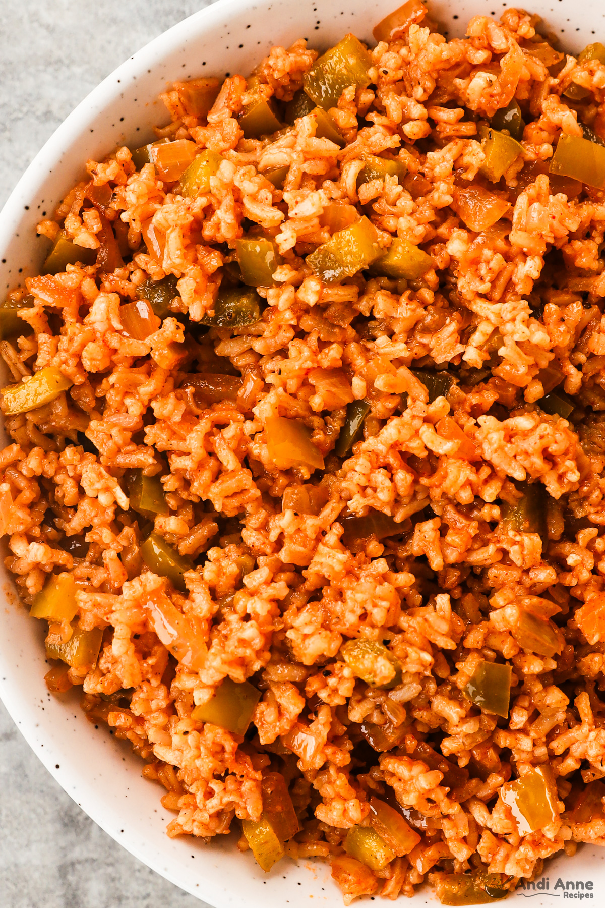 cajun rice in a bowl with chopped bell pepper and onion