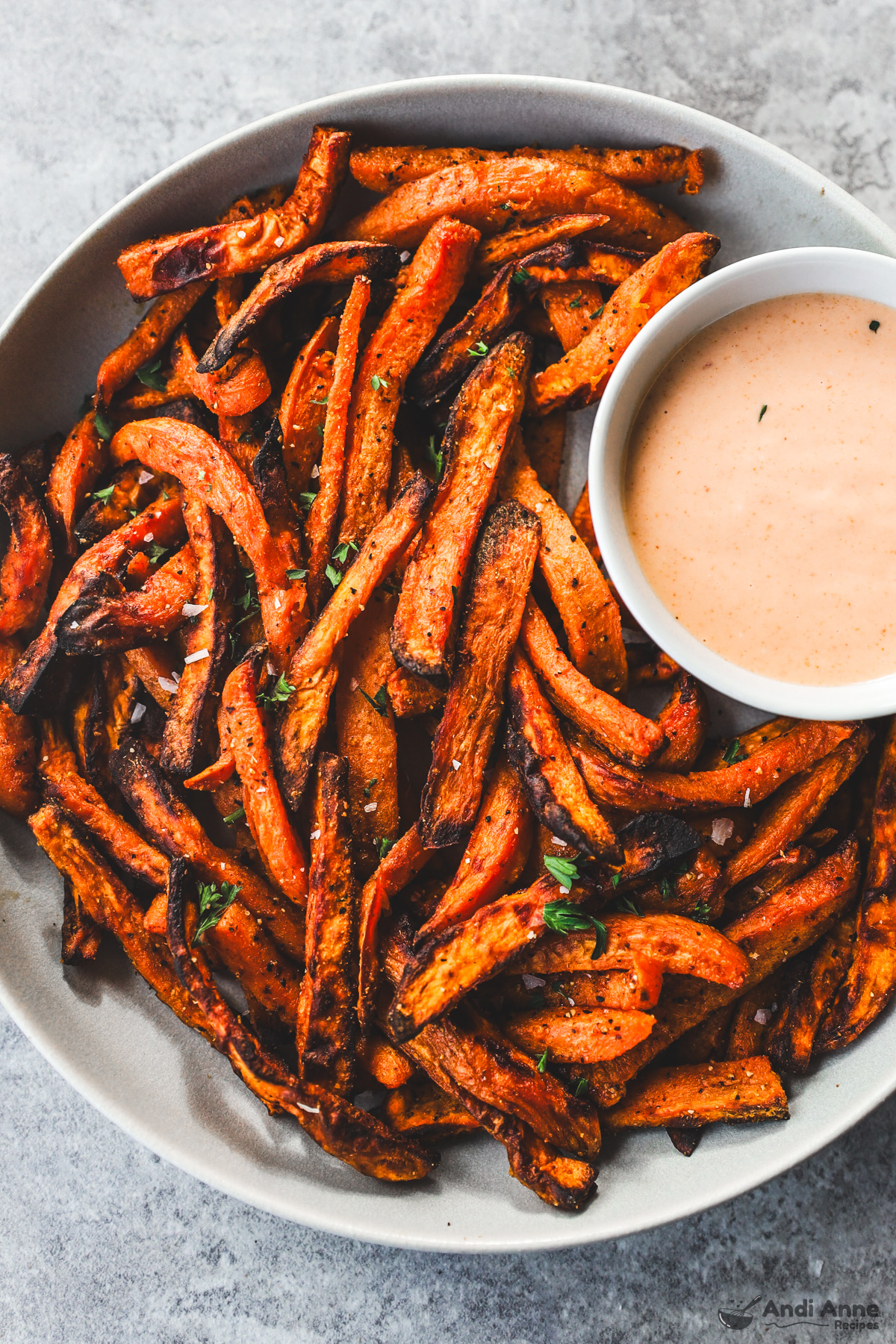 Plate with crispy sweet potato fries and a dipping sauce on the side