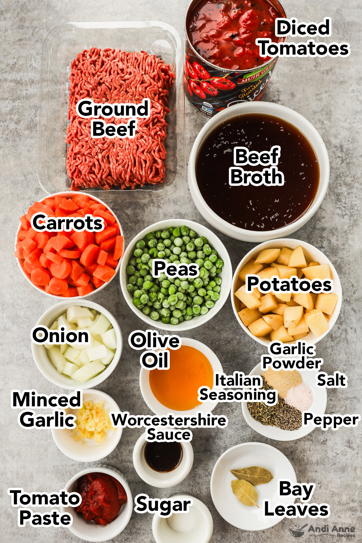 Recipe ingredients in bowls, including raw ground beef, diced tomatoes, beef broth, carrots, peas, chopped potatoes, spices, tomato paste, oil and garlic.